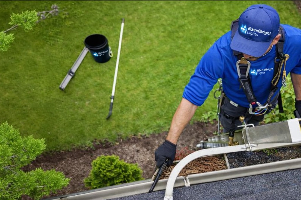 BlendBright technician clearing debris from a residential gutter