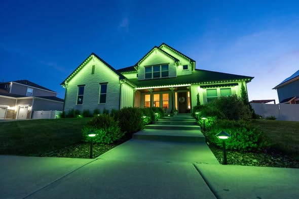Home at dusk with green LED accent lighting on rooflines, paths, and landscaping